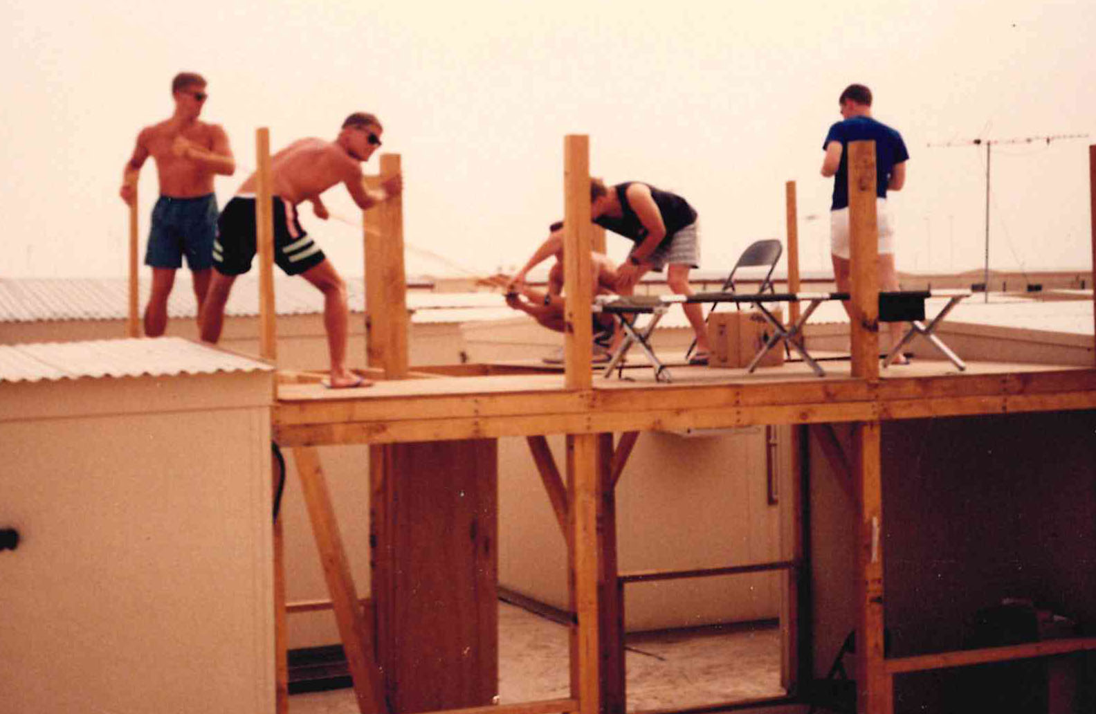 Scrap lumber, two-by-fours, and a desert sky — the squadron building its own quarters at Al Minhad.